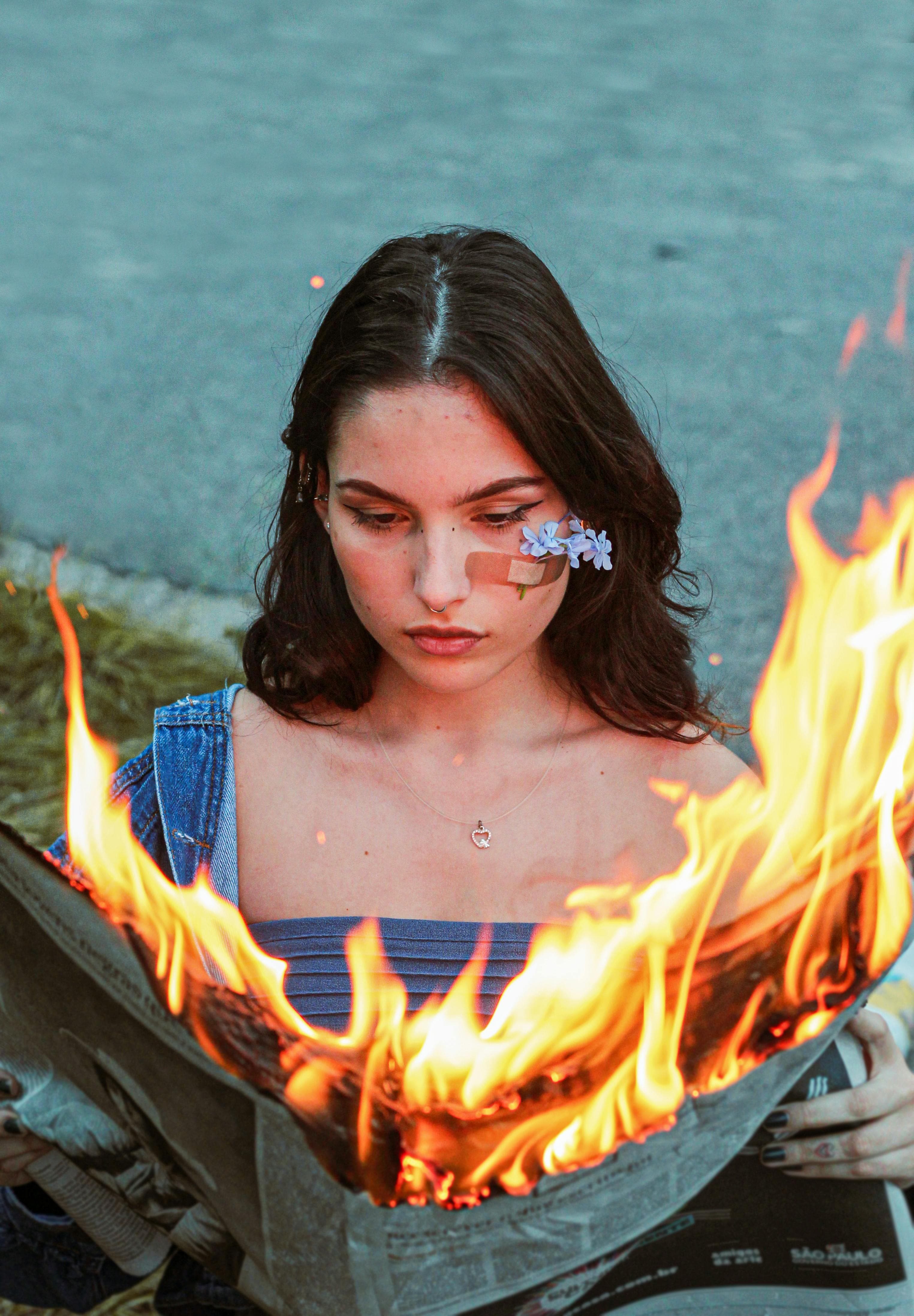 A woman reads a newspaper on fire.